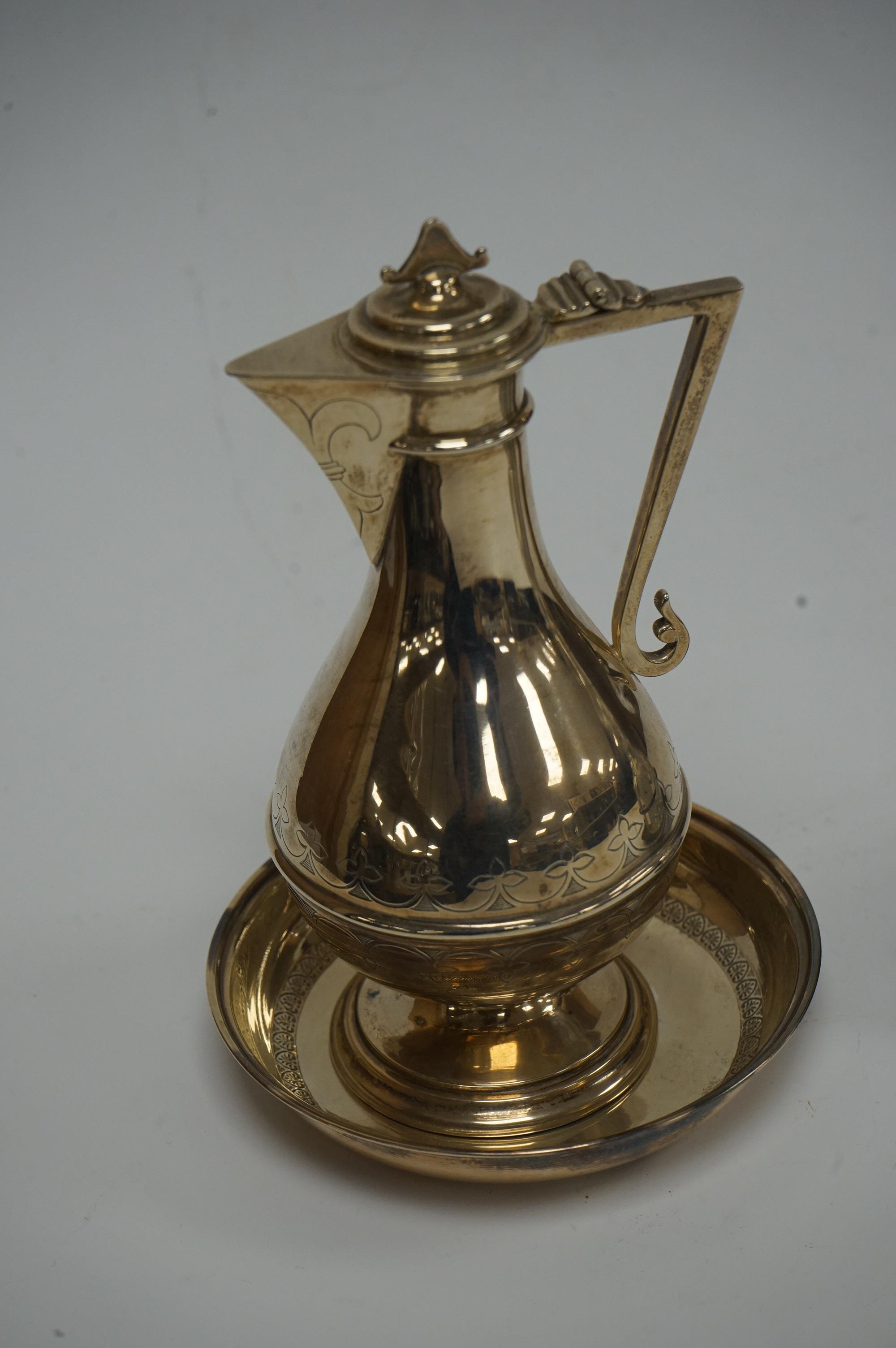 An Edwardian silver communion jug, by James Deakin & Sons, London, 1908, 15.2cm, together with a late Victorian repousse silver cruet stand with two glass bottles and stoppers, James Dixon & Sons, Sheffield, 1897 and a c